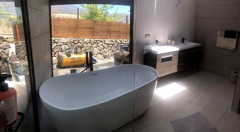 Baño con tina y gran ventanal hacia el exterior