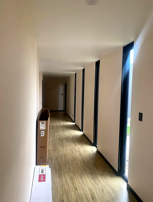 Pasillo interior con piso de madera y ventanales